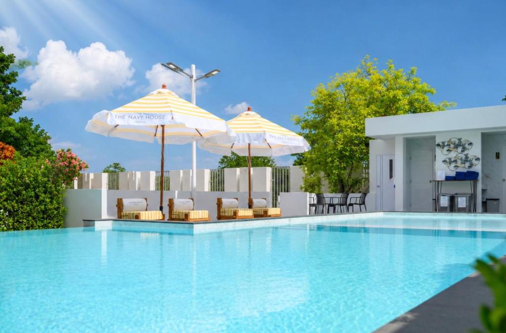 a swimming pool with two umbrellas and chairs at THE NAVY HOUSE HOTEL in Sattahip
