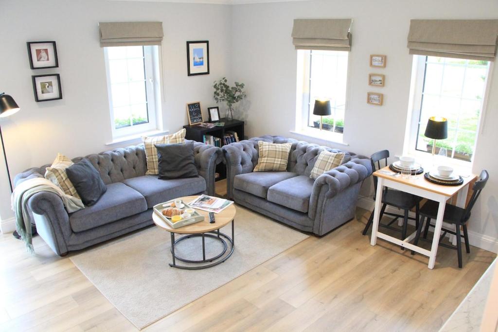 a living room with two couches and a table at Sundaywell Cottage in Killyleagh