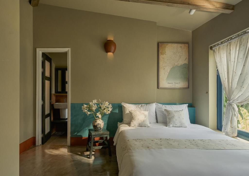 a bedroom with a bed and a vase of flowers on a table at TONG Boutique Hotel in Phan Thiet