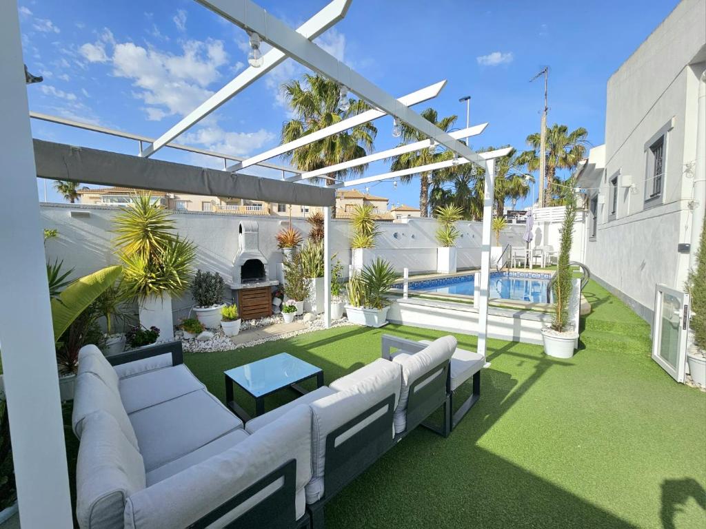 an outdoor patio with white furniture and a pool at Chalet con Piscina Privada, Aguas Nuevas, Torrevieja in Torrevieja