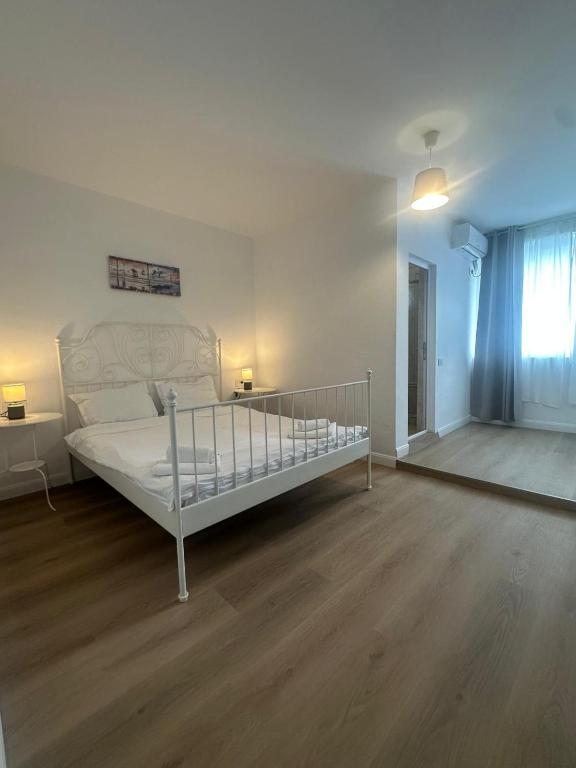 a bedroom with a white bed and a wooden floor at Vila DVG Tineret in Schitul