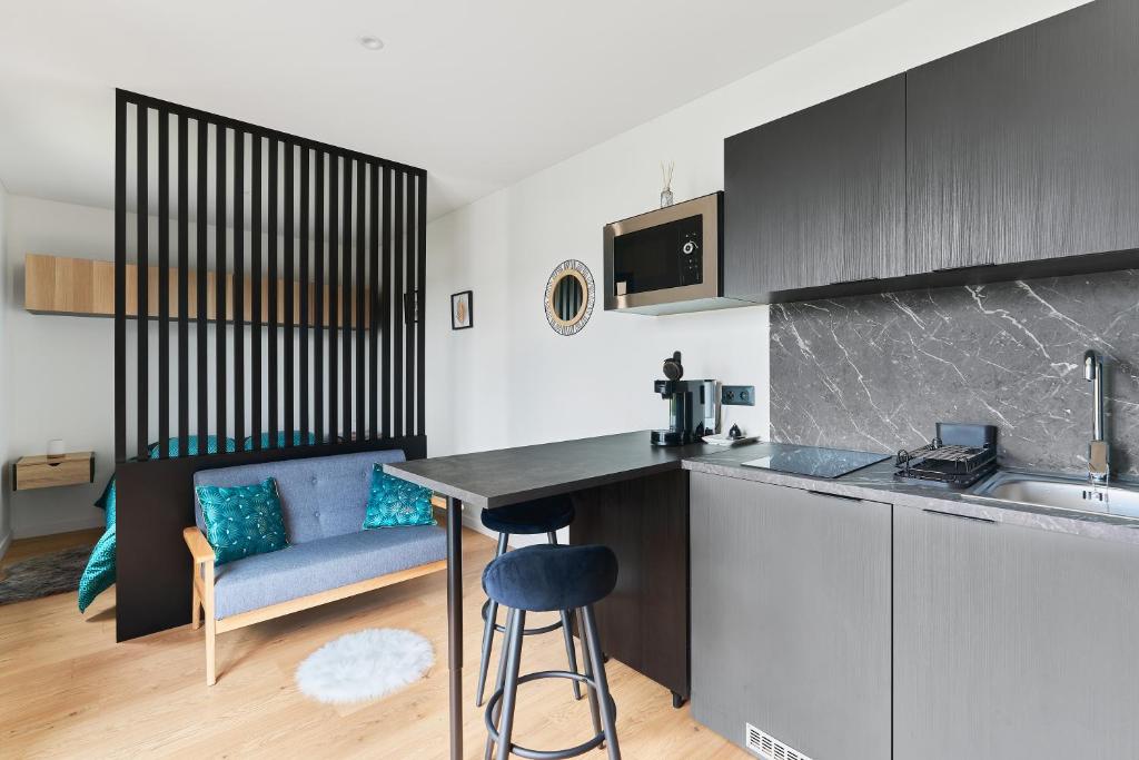 a kitchen with a table and a couch in a room at Le Cocon de Brocéliande - Studio cosy et indépendant in Saint-Thurial