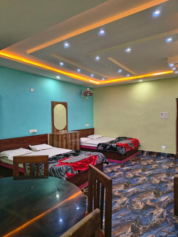 a room with three beds and a table and chairs at Hotel Parinay Vatika in Deoghar