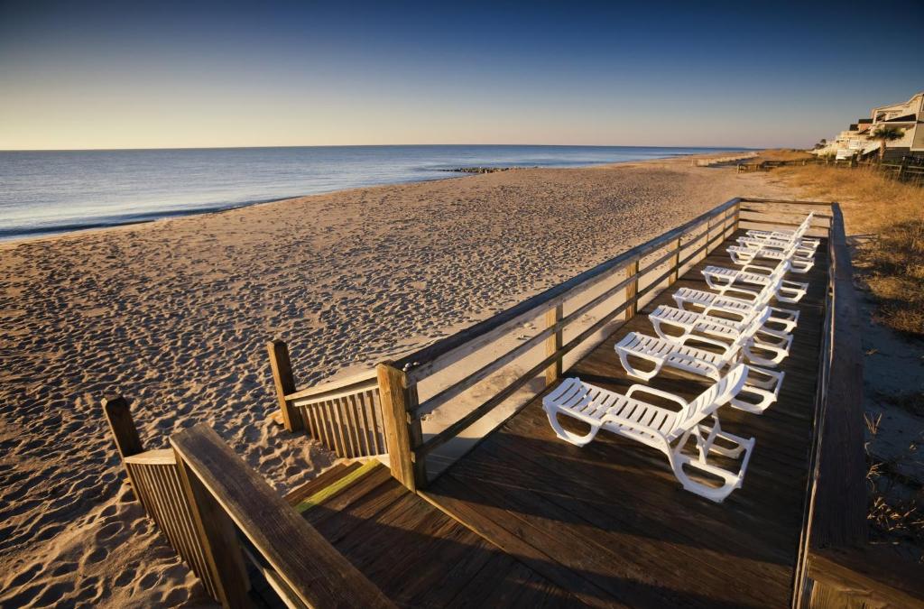 a row of white chairs on the beach at Ocean Ridge Resort 4BR Apartment in Edisto Island