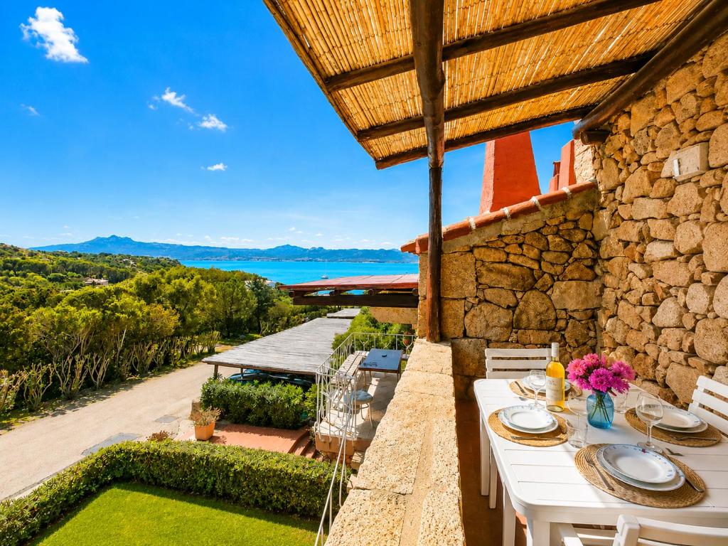 a patio with a table and a view of the ocean at Casa al mare Porto Sole in Baja Sardinia