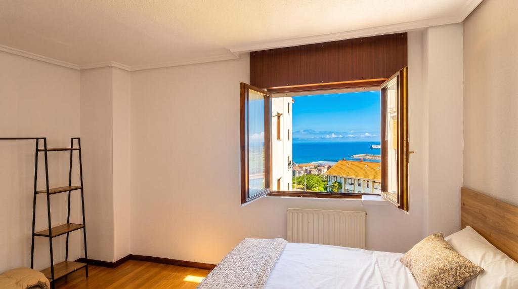 a bedroom with a window with a view of the ocean at Las Vistas in Suances