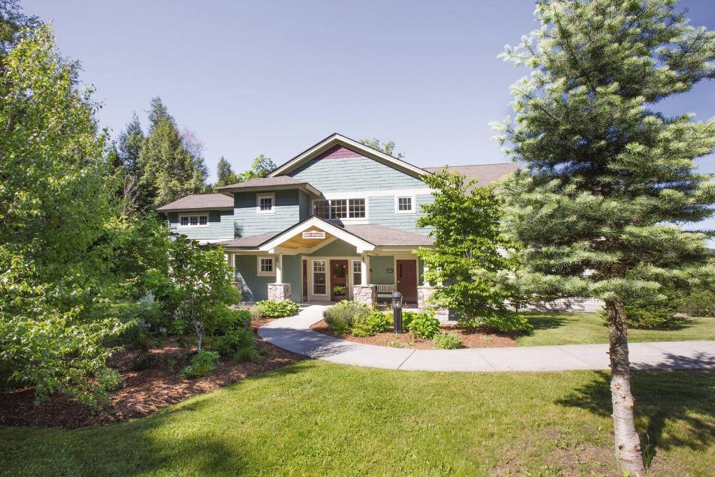 a white house with a tree in the yard at Smugglers' Notch Resort 2BR Apartment in Cambridge