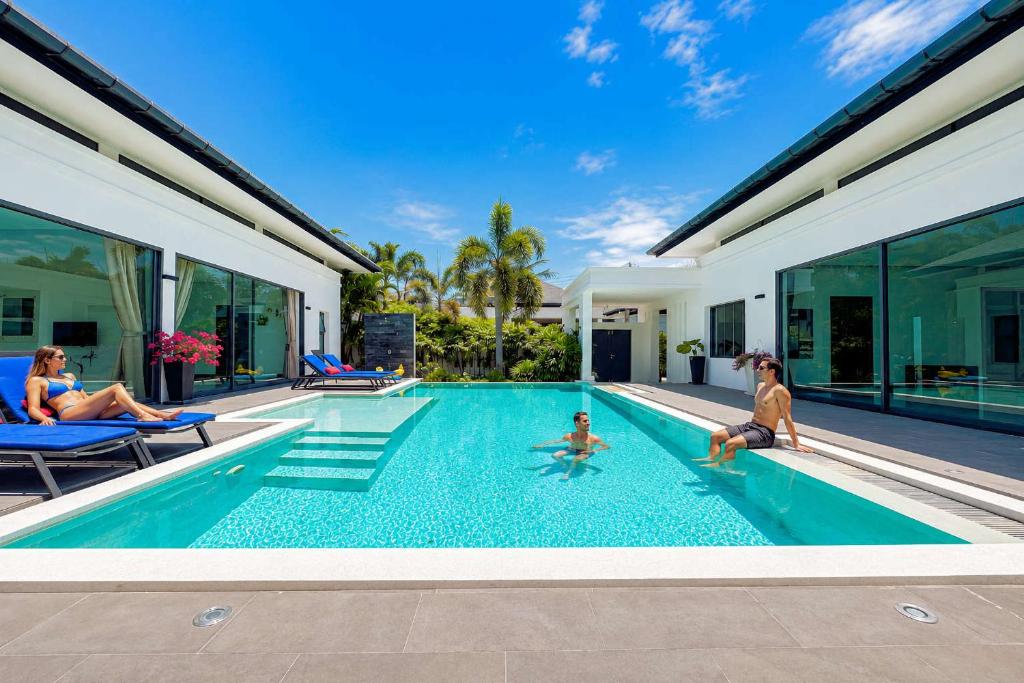 a family playing in the swimming pool of a house at Exclusive Tropical Living! Elegant 4BR Villa Destiny with Salt Pool in Rawai Beach