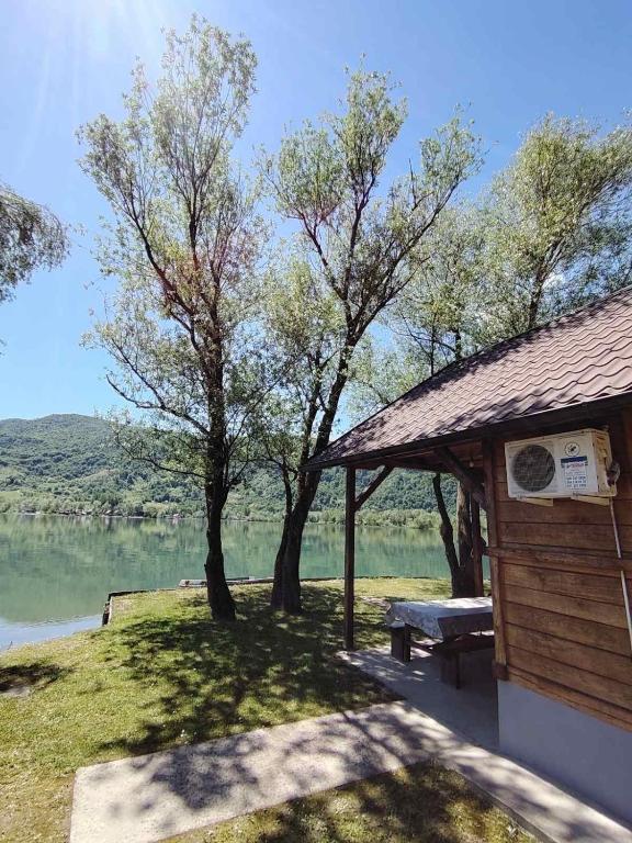 a building with a picnic table next to a lake at Drinski Mir in Mali Zvornik