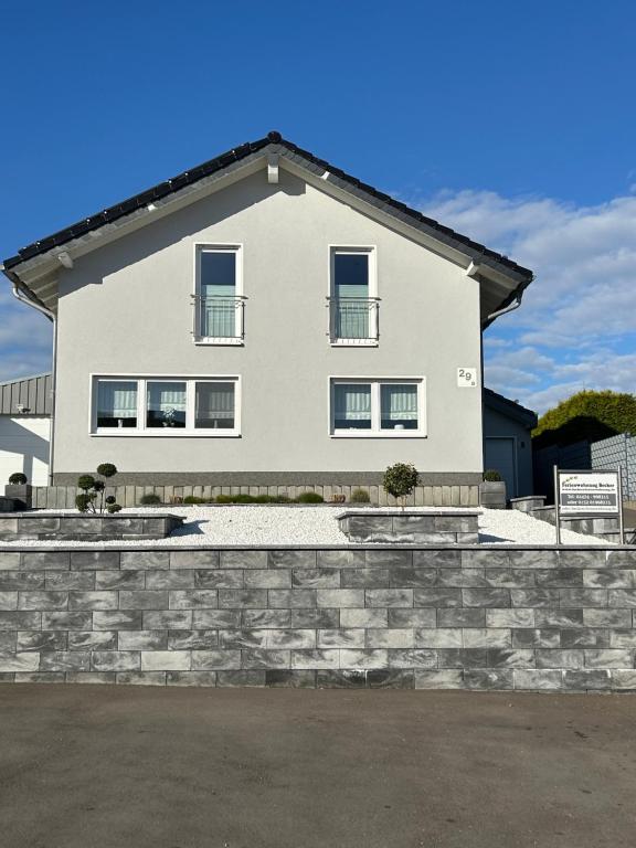 a large white house with a stone wall at Ferienwohnung Becker in Nideggen