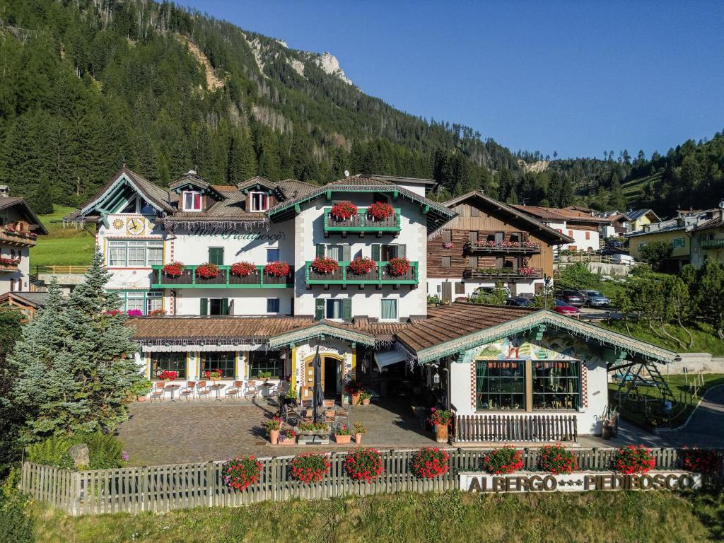 a large building with flowers in front of a mountain at Hotel Piedibosco in Moena
