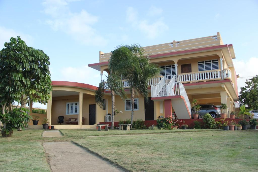 a house with a balcony and a yard at Jardin del Mar Guesthouse in Hatillo