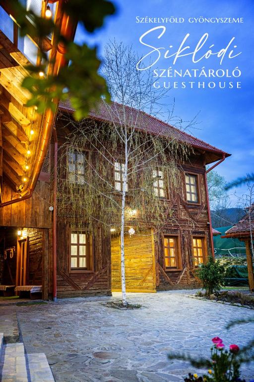 a log house with a tree in front of it at Székelyföld,Siklódi Kő Vendégház Szénatároló in Şiclod