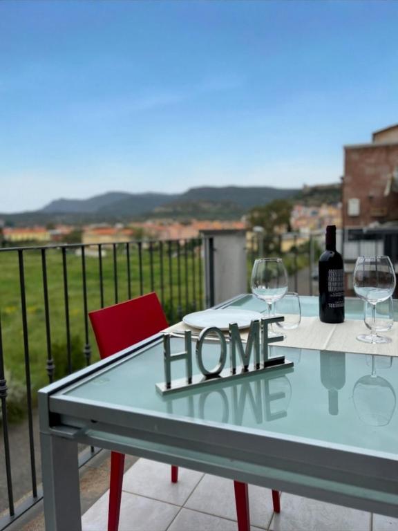 a glass table with wine glasses and a sign that reads home at Sunset Apartment 2Bedr Sunset View Parking in Bosa