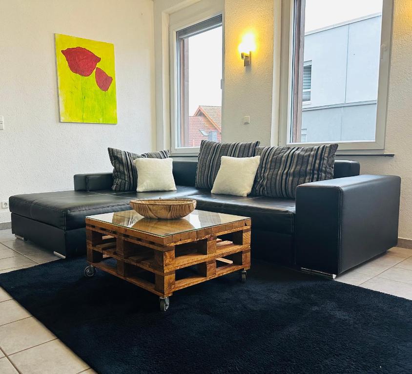 a living room with a black couch and a coffee table at Loft im Fabrikstil mit 2 eigenen Schlafzimmern mit Wlan und Parkplatz in Groß-Umstadt