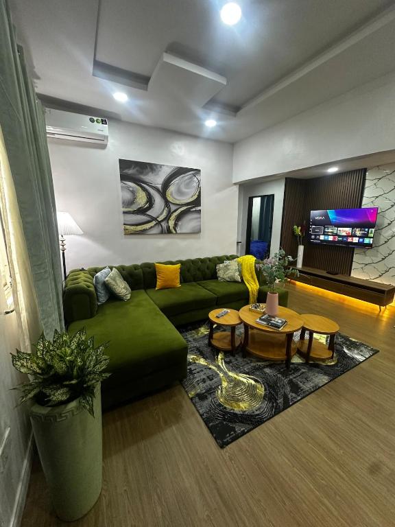 a living room with a green couch and tables at Hope Apartments Surulere in Lagos