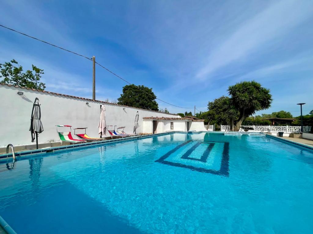 a swimming pool with blue water in front of a building at VILLA PRAXEDES con piscina a Nettuno in Nettuno