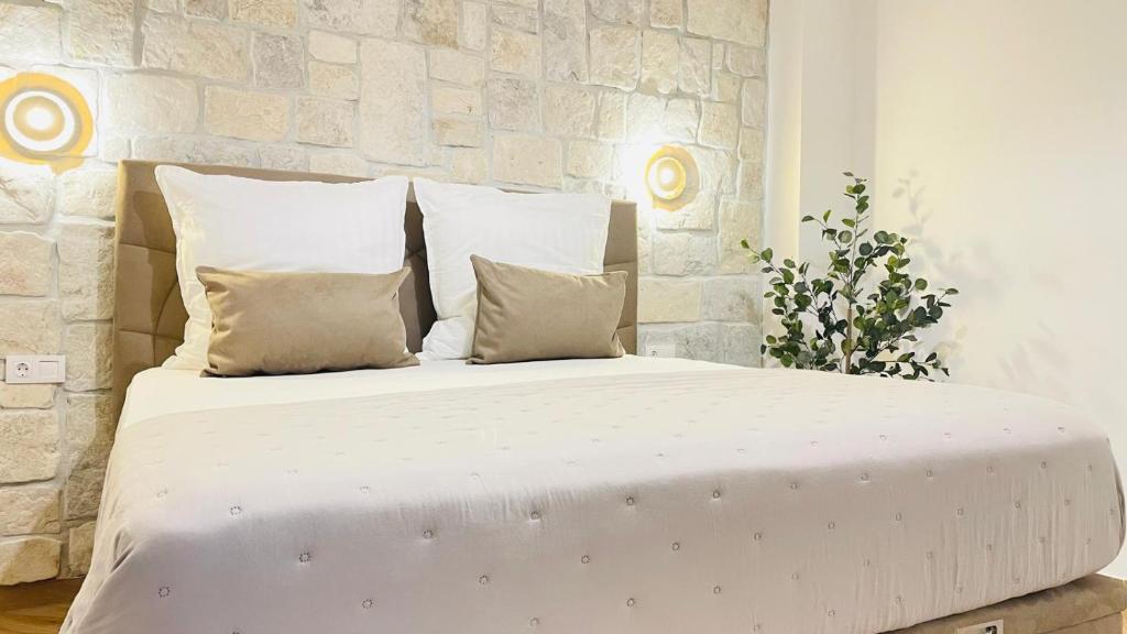 a bed with white sheets and pillows in a room at Stonehouse-Pag in Povljana
