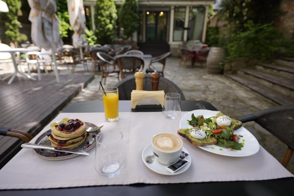 a table with two plates of food and a cup of coffee at Barrique 17 - Breakfast at Restaurant & Minibar - Old Town in Braşov