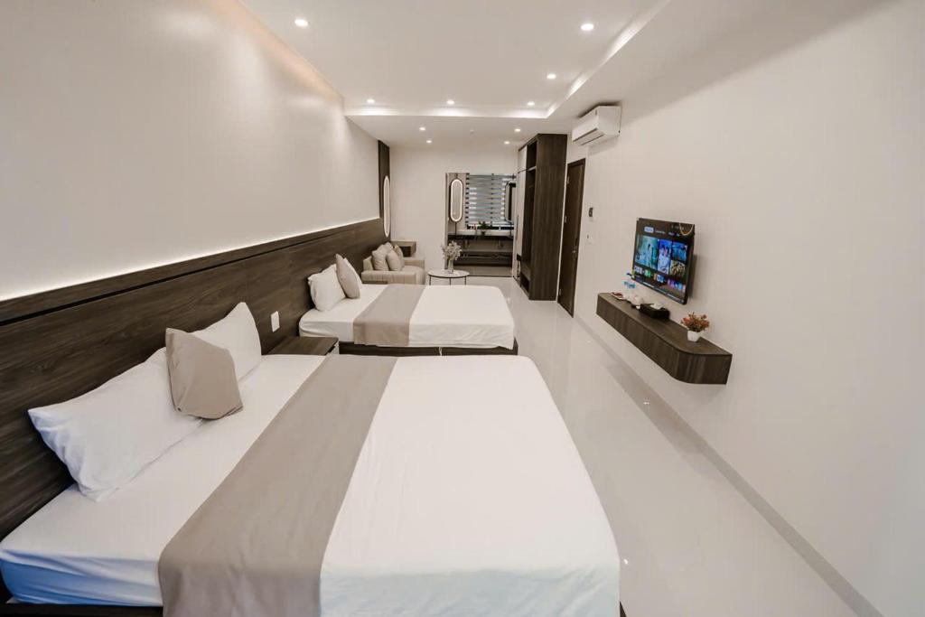 a hotel room with two beds and a flat screen tv at Vui Hotel in Sầm Sơn