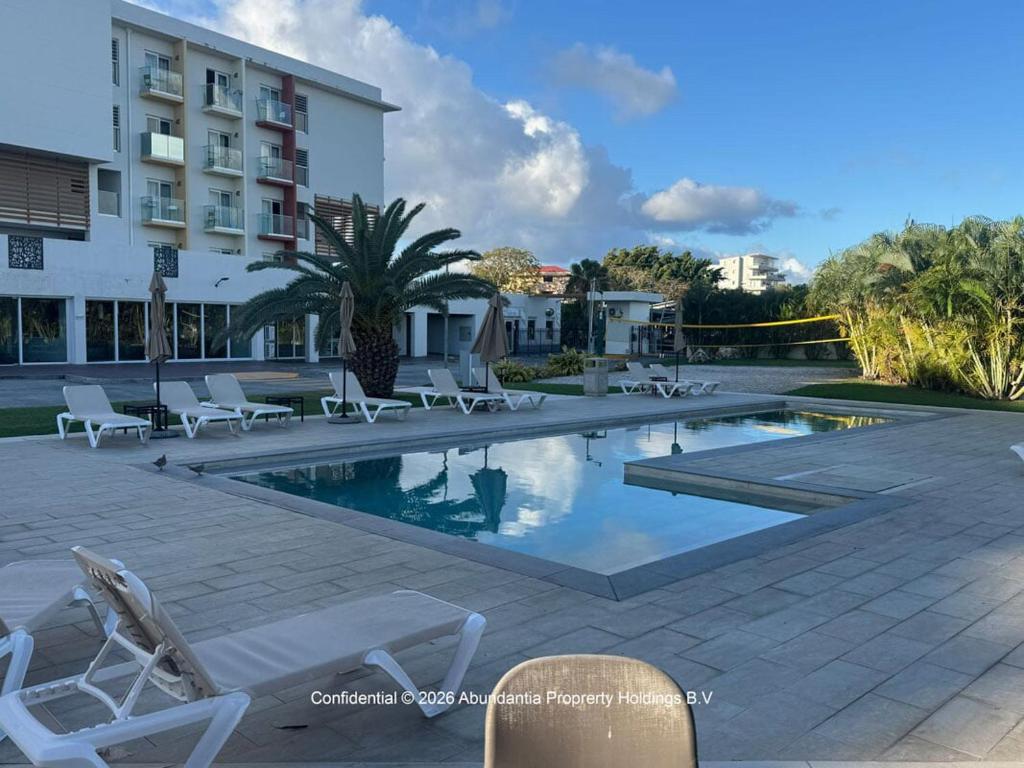 a swimming pool with lounge chairs and a building at studio to Maho in Cupecoy