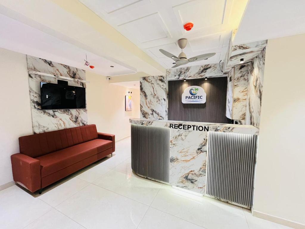 a lobby with a red couch and a reception desk at Hotel Pacific Empire in Ahmedabad