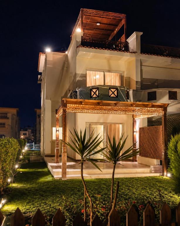 a house at night with a palm tree in front at Luxury Seaside Villa Direct Pool Access, Private Garden & Rooftop Stella Heights Sidi Abdelrahman فيلا مميزه جدا في الساحل الشمالي ستيلا هايتس سيدي عبدالرحمن in El Alamein