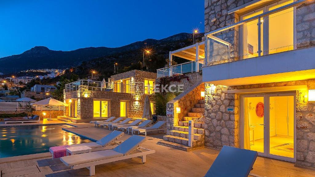 a house with a swimming pool and chairs next to a building at TEKCE Villa Dolly N24 in Kalkan