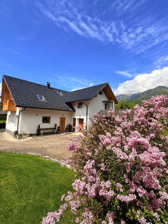 a house with pink flowers in front of it at Slosarjeva Holiday House - Alpine View & Modern Comfort in Preddvor
