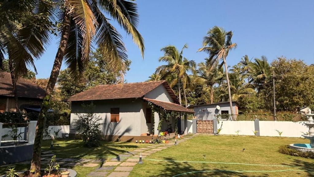 a house with a yard and palm trees at Shanti Niketan in Kārwār