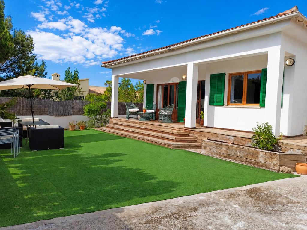 a house with a green lawn in front of it at Vila Mimosa in Colonia de Sant Pere