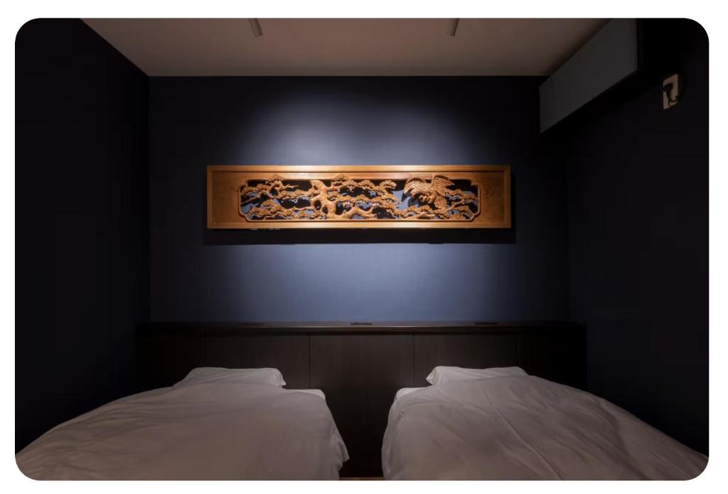 two beds in a room with a painting on the wall at yah homes takasago in Fukuoka