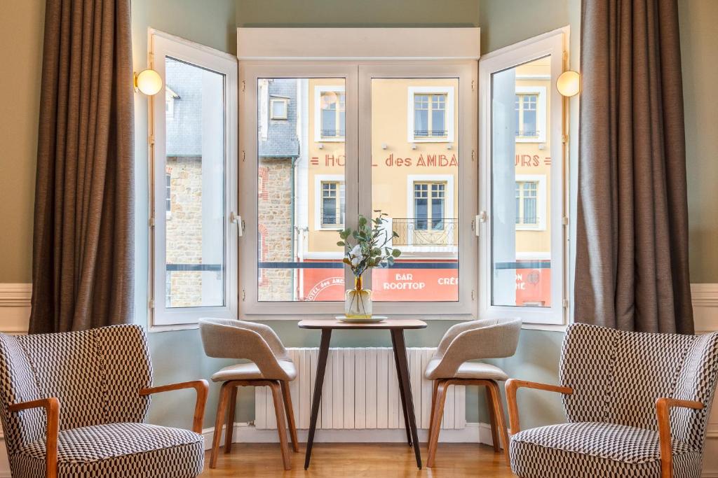 a room with chairs and a table in front of windows at La Villa du Sillon by les Ambassadeurs - Saint Malo Plage in Saint Malo