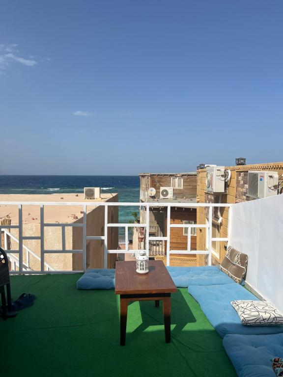 a table on a balcony with a view of the beach at Zalooma House I Beachfront Hostel Dahab in Dahab