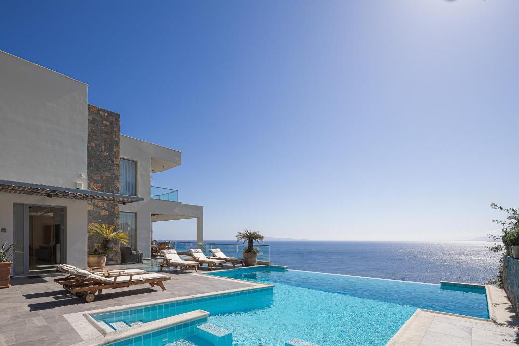 a villa with a swimming pool next to the ocean at Candia Lux in Heraklio