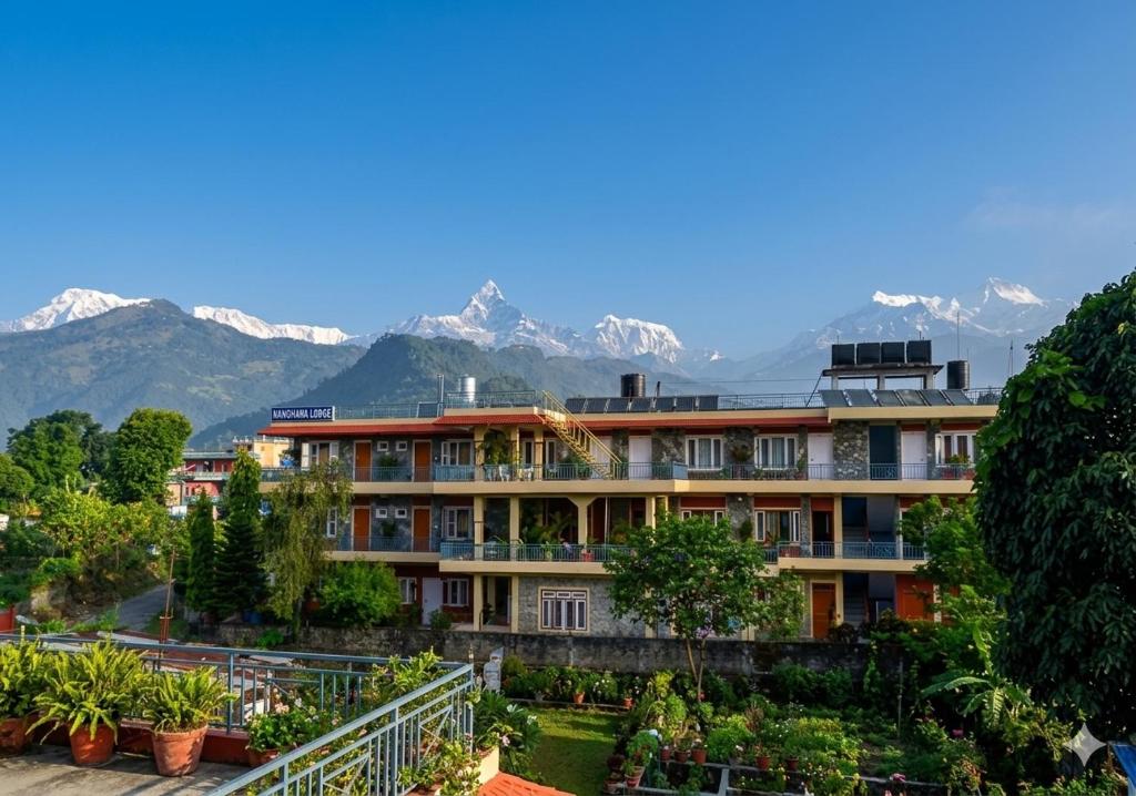 a large building with mountains in the background at Nanohana Lodge in Pokhara