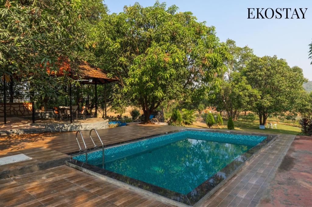 a swimming pool in a yard with trees at EKOSTAY - Brick Wood in Karjat