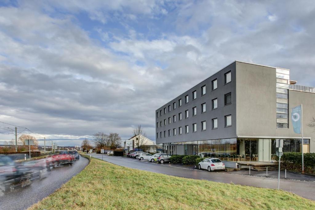 a building on the side of a street with parked cars at eXo Fly Level 4 Hotel Stuttgart-Flughafen in Ostfildern