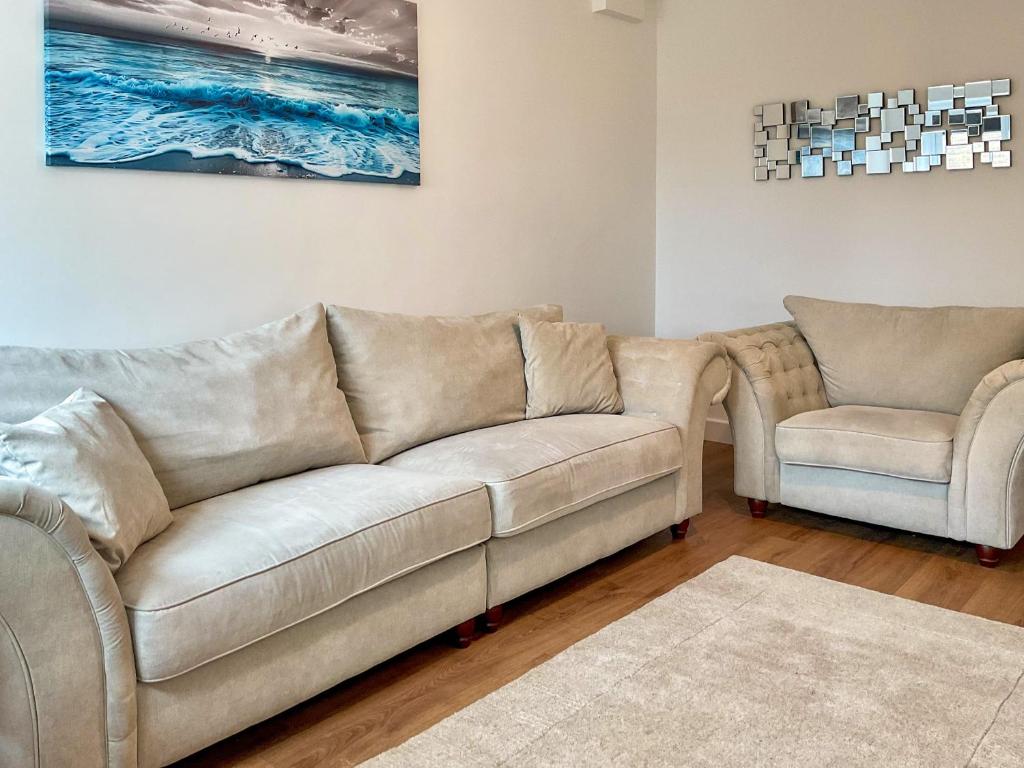 a living room with a couch and two chairs at White Sands Cottage in Weymouth