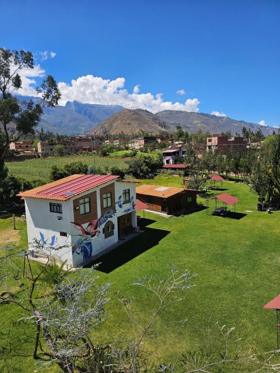 a small white house with a red roof on a green field at Apu Ecolodge in Caraz