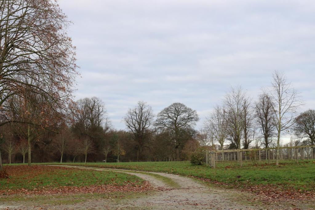 a dirt road in a field with trees and a fence at BroomfieldBarns1A in Swettenham