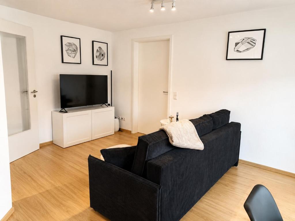 a living room with a black couch and a television at Gemütliches Apartment 8 am Titisee mit Balkon, Top Lage, Parkplatz in Titisee-Neustadt