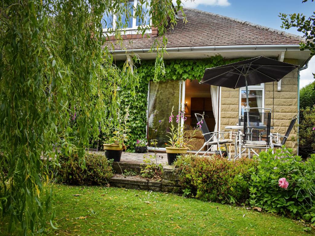 a house with a table and an umbrella in the yard at New Meadows Cottage in Pickering