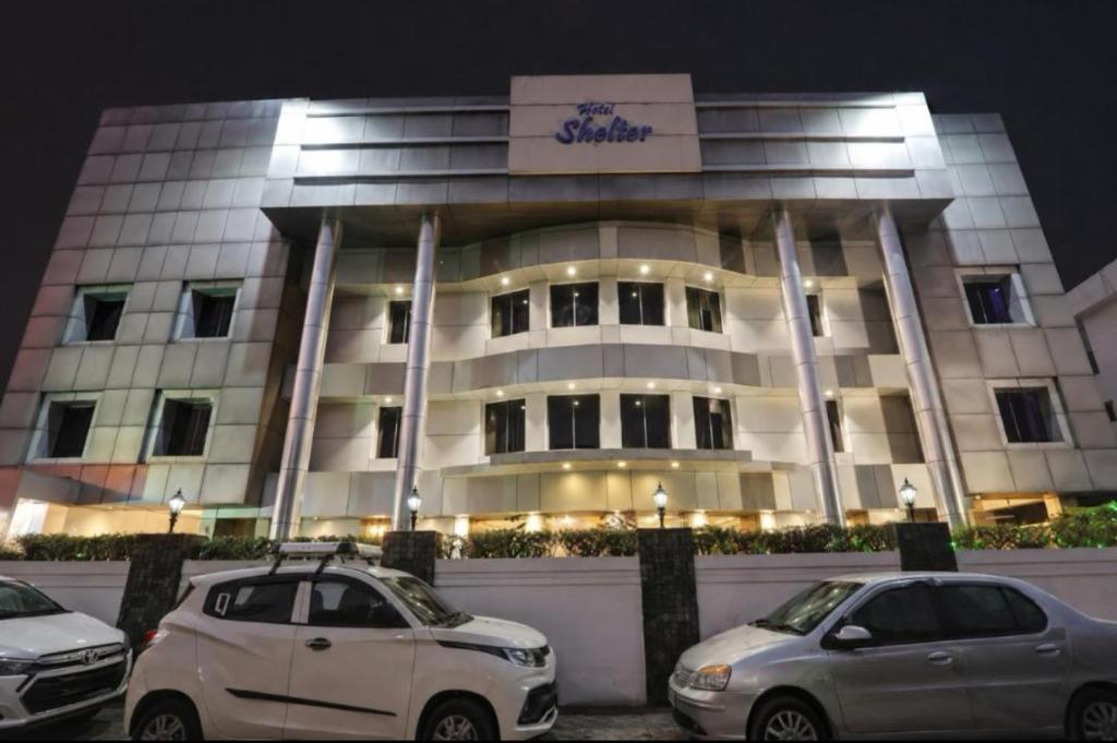 two cars parked in front of a building at night at SHELTER HOTEL in Lucknow