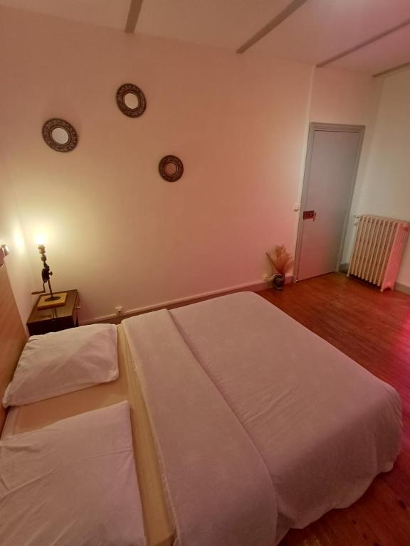 a bedroom with two beds and a table and clocks on the wall at La Flûte 2 in Thiers