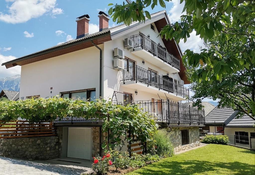 a large white building with balconies and a yard at Apartments & Rooms Aleksandra in Bled