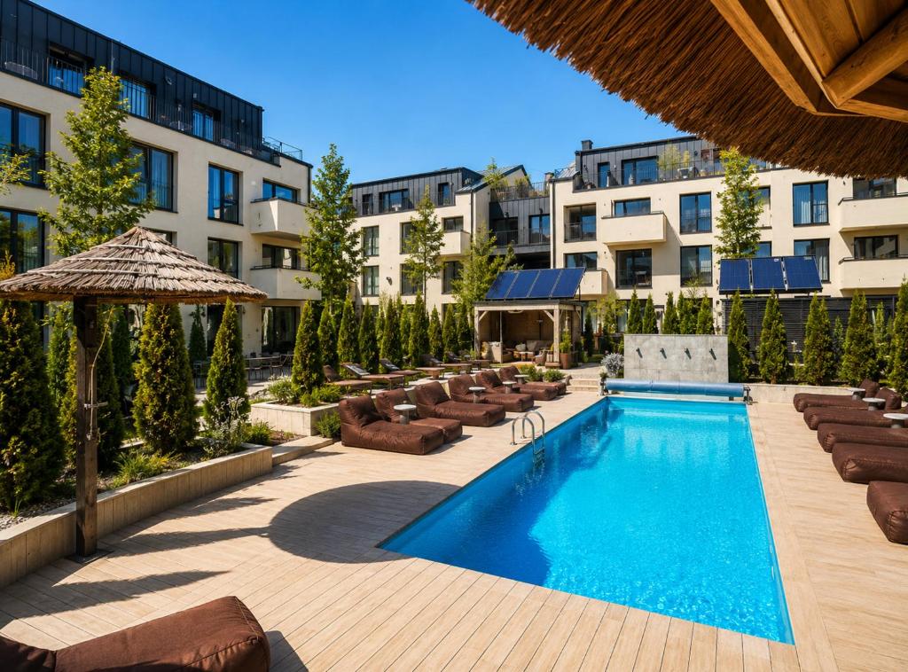 a pool with chairs and umbrellas next to a building at Maluno vilos apartamentas su terasa in Palanga