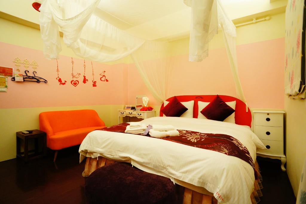 a bedroom with a bed and an orange chair at Sweet Rainbow B&amp;B in Hualien City