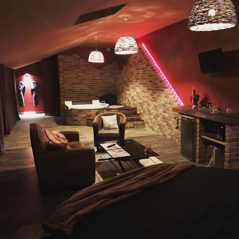 a living room with a couch and a brick wall at chambre INNAMORATO avec jacuzzi lit rond et jardin avec piscine in Saint-Martial-sur-Né