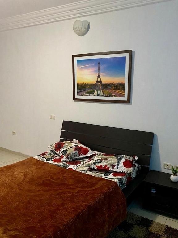 a bedroom with a bed with a picture of the eiffel tower at Le palmier in Mezraya